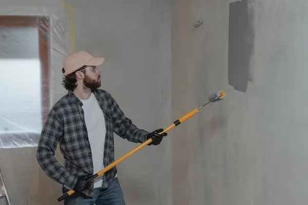 Painter rolling grey paint onto an interior wall in Oceanside